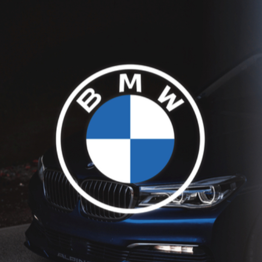 BMW-Logo in Weiß-Blau auf einem dunklen Hintergrund vor einem BMW-Fahrzeug.