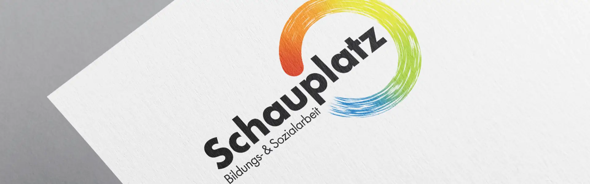 Schauplatz Logo mit Subline Bildungs- und Sozialarbeit und einem bunten Kringel